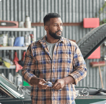 Asthma patient Craig standing in front of a car in an automotive workshop Asthma patient Craig standing in front of a car in an automotive workshop